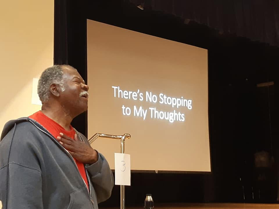 rehearsal of There's No Stopping to My Thoughts, Leon Kennedy in front of mic, eyes closed, at a rehearsal of a play inspired by events in his life.
